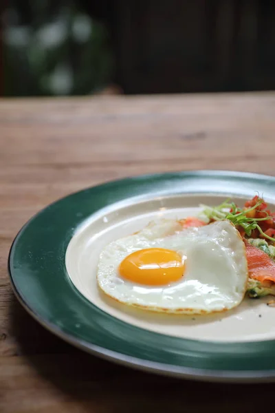 Zucchini fritters with egg and smoked salmon on wood background vinage style