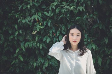 Açık şehir arka planında modern tarzda düşünen ve görünen genç bir kadın portresi.