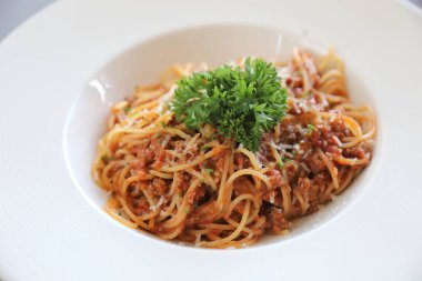 Parmesan peyniri ve fesleğenle süslenmiş kıyma ve domates soslu spagetti bolonez, İtalyan yemeği.