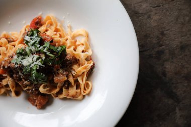 Koyu tonu mistik ışık tarzı ahşap arka plan üzerinde sığır eti ve domates soslu makarna Fettuccine Bolognese