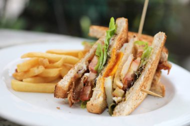 Club sandviç, yumurta pastırmalı tavuk domates ile kızarmış açık restoran arka plan ile sandviç