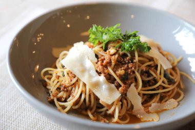 Parmesan peyniri ve fesleğenle süslenmiş kıyma ve domates soslu spagetti bolonez, İtalyan yemeği.