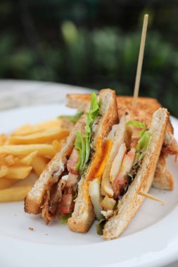 Club sandviç, yumurta pastırmalı tavuk domates ile kızarmış açık restoran arka plan ile sandviç