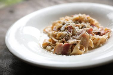 Makarna beyaz soslu domuz eti ve mantar mistik ışık ahşap arka plan üzerinde