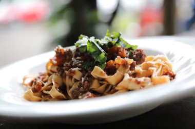 Koyu tonu mistik ışık tarzı ahşap arka plan üzerinde sığır eti ve domates soslu makarna Fettuccine Bolognese