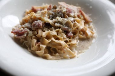 Makarna beyaz soslu domuz eti ve mantar mistik ışık ahşap arka plan üzerinde