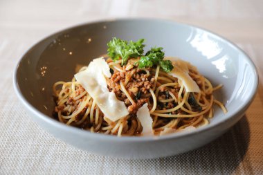 Parmesan peyniri ve fesleğenle süslenmiş kıyma ve domates soslu spagetti bolonez, İtalyan yemeği.