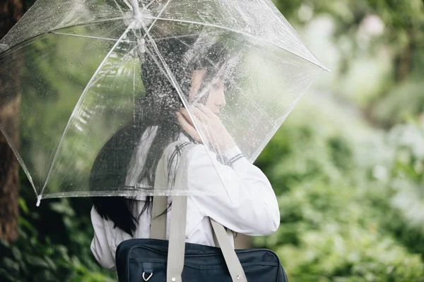 亚洲女学生的肖像看着自然人行道在下雨 — 图库照片