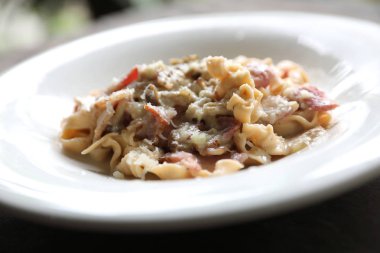 Makarna beyaz soslu domuz eti ve mantar mistik ışık ahşap arka plan üzerinde