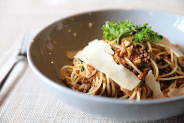 Parmesan peyniri ve fesleğenle süslenmiş kıyma ve domates soslu spagetti bolonez, İtalyan yemeği.