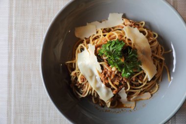 Parmesan peyniri ve fesleğenle süslenmiş kıyma ve domates soslu spagetti bolonez, İtalyan yemeği.