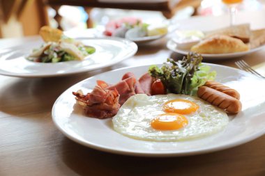 Kahvaltı kızarmış yumurta, pastırma, sosis, fasulye, tost, taze salata ve meyve üzerinde ahşap masa ayarla