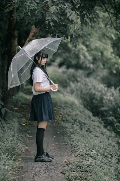 在雨中漫步在自然人行道上的亚洲学校女孩肖像 — 图库照片