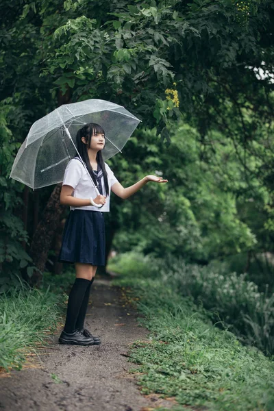 在雨中漫步在自然人行道上的亚洲学校女孩肖像 — 图库照片