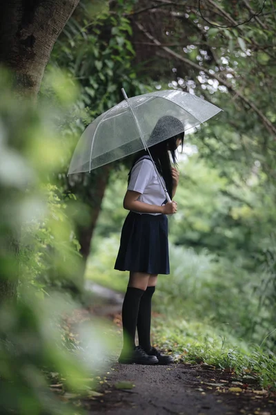 在雨中漫步在自然人行道上的亚洲学校女孩肖像 — 图库照片