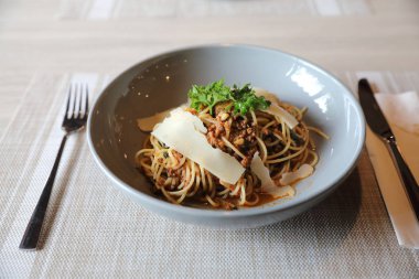 Parmesan peyniri ve fesleğenle süslenmiş kıyma ve domates soslu spagetti bolonez, İtalyan yemeği.