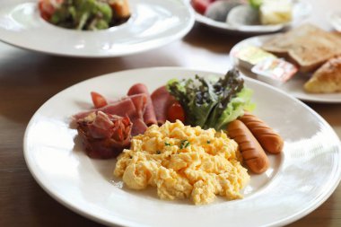 Pastırma sosis ve ahşap zemin üzerine salata ile çırpılmış yumurta Kahvaltı