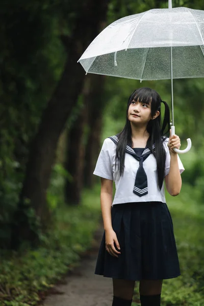 在雨中漫步在自然人行道上的亚洲学校女孩肖像 — 图库照片