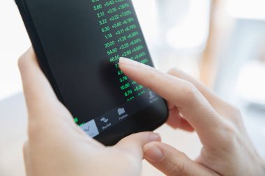 Akıllı telefon ile çalışan bir kadın kahve dükkanında hisse senedi ticareti, iş konsepti