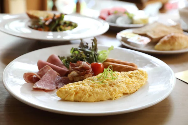 早餐设置煎蛋卷与香肠培根和沙拉在木背景 — 图库照片