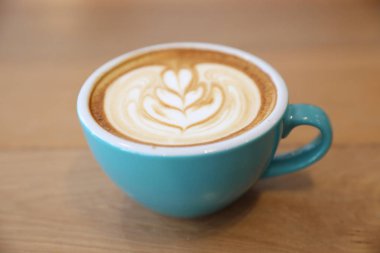 Kahve dükkanında, ahşap masada sıcak kapuçino.