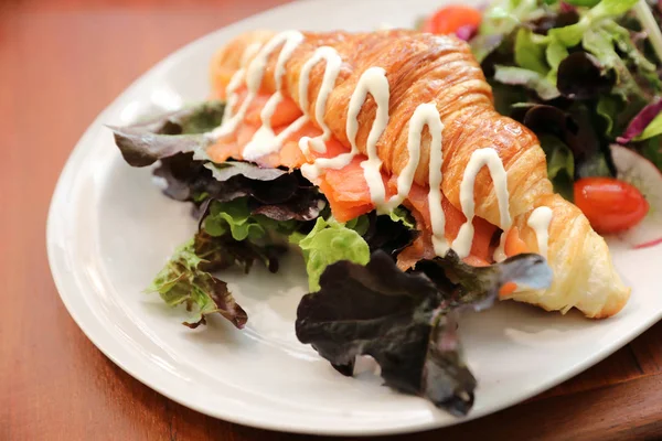 Kruvasan ekmek somon ve ahşap zemin üzerine salata ile