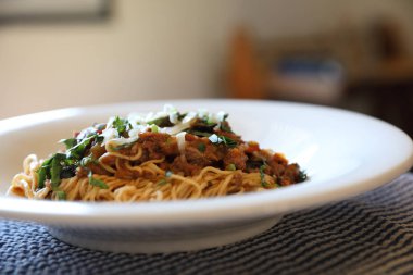 Parmesan peyniri ve fesleğenle süslenmiş kıyma ve domates soslu spagetti bolonez, İtalyan yemeği.