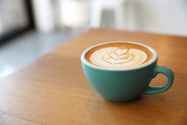 Kahve dükkanında, ahşap masada sıcak kapuçino.