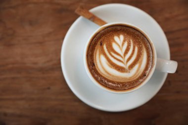 Kahve dükkanının ahşap masasındaki sütten yapılmış kapuçino ya da Latte sanat kahvesi.