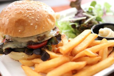 Sığır eti Hamburger patates kızartması ve salata ahşap arka plan üzerinde