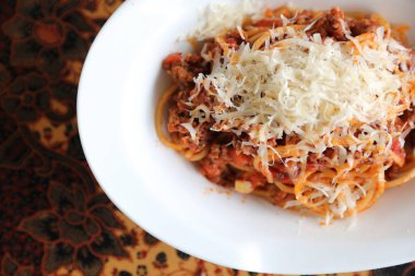 Parmesan peyniri ve fesleğenle süslenmiş kıyma ve domates soslu spagetti bolonez, İtalyan yemeği.