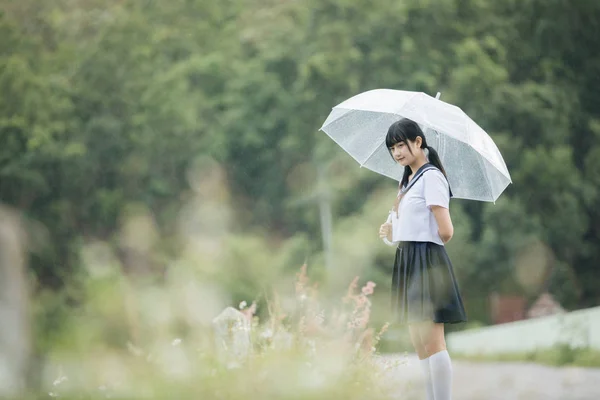 在雨中漫步在自然人行道上的亚洲学校女孩肖像 — 图库照片