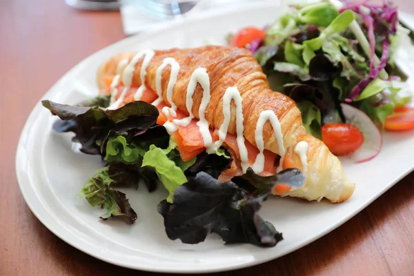 Croissant bread with salmon and salad on wooden background — Stock Photo, Image