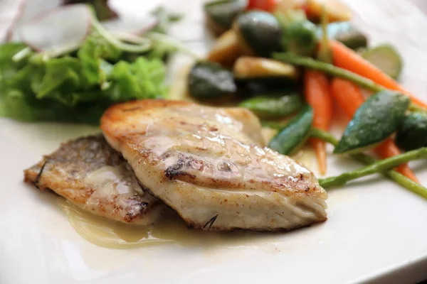 Ikan laut dengan sayuran panggang dan salad di meja kayu — Stok Foto