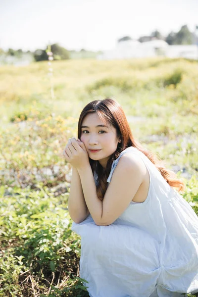 Porträt einer jungen asiatischen Frau sitzt und lächelt in einer Blume — Stockfoto