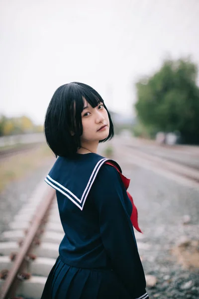 Ritratto di asiatica giapponese scuola ragazza costume guardando railwa — Foto Stock