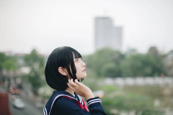 Asiatische Schulmädchen suchen und denken in städtischen Hintergrund — Stockfoto