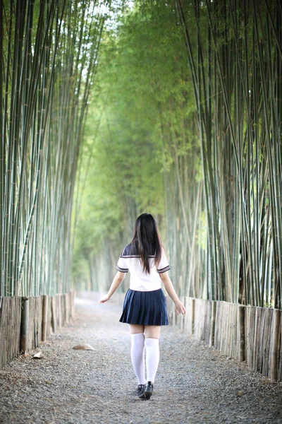 美しいアジア系日本人女子高生の制服の肖像竹の森の背景 — ストック写真