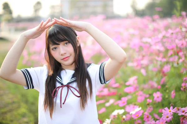 ピンクのコスモスの花で統一された日本の女子高生の肖像 — ストック写真
