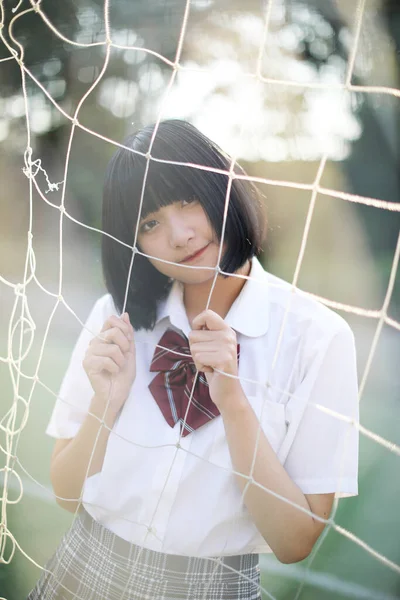 美しいですアジアの日本の高校生の女の子制服見ますとともにネットで緑の背景 — ストック写真