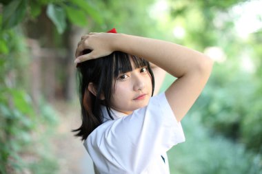 Asyalı liseli kız ağaç geçmişi olan bir şehirde yürüyor ve arıyor.