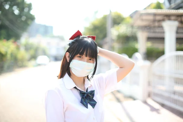 Asian school girl with mask in urban city with tree background