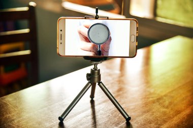 Oturma odasında bir tripod üzerinde smartphone içinde doktor muayenesi