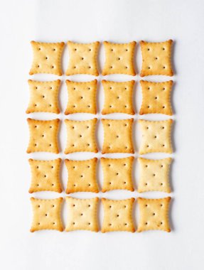 Beyaz arka planda dört köşeli bisküvi krakerleri.