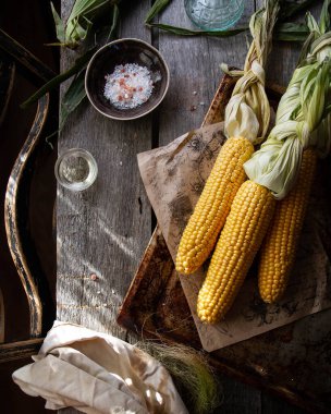 Eski tahtalardan yapılmış bir masada metal bir tepside mısır. Tuz ve yağa yakın atmosfer. Örgü, kırsal, üst görünüm