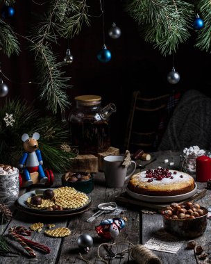 Noel masası turta, waffle, tatlı ve fındık, oyuncaklar ve tatil dekoruyla süslenmiş, kırsal