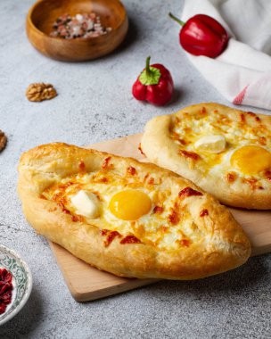 Peynirli, yumurtalı ve tereyağlı Gürcistan hamur işi Khachapuri tekneleri, gri bir masada.