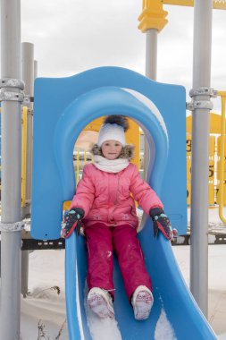 Genç kız kış aylarında slayt üzerinde kayar