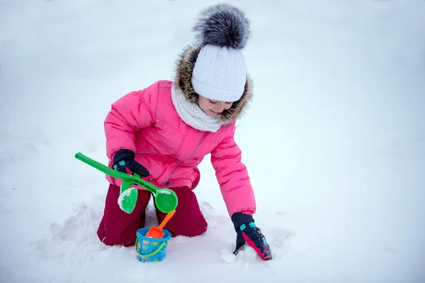 雪で遊んで 雪玉を作る女の子 — ストック写真