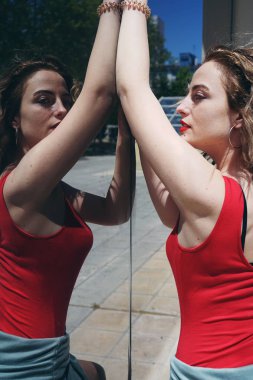 ayna yakınındaki yaz aylarında açık kırmızı gömlekli genç güzel kıvırcık kadın fotoğrafı